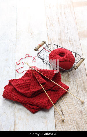 Foulard rouge, tricoté main balle de fils et aiguilles à tricoter pour cadeau de Noël fait main Banque D'Images