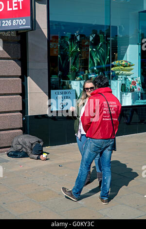 Un organisme de bienfaisance, travailleur ou tapin, travaillant pour la Croix Rouge Britannique affronte un piéton sur Princes Street, Édimbourg, Écosse, Royaume-Uni. Banque D'Images