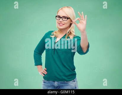 Jeune femme avec des lunettes montrant ok Banque D'Images