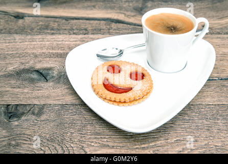 Tasse de café avec biscuits de smiley sur fond de bois. Drôle de petit-déjeuner Banque D'Images