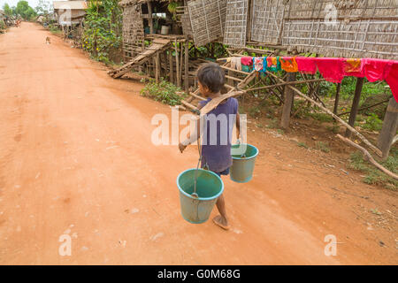 Un garçon porte seaux pour recueillir l'eau potable. Chong Kneas village flottant. Le Cambodge. Banque D'Images