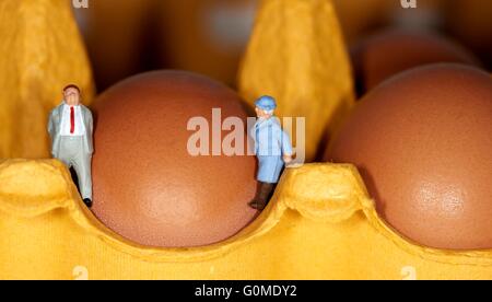 Un couple retraité figurine miniature debout sur un oeuf boîte à côté de 2 oeufs Banque D'Images