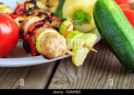 Poulet grillé et légumes sur des brochettes en bois sur fond de bois Banque D'Images