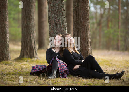 Jolies filles amis assis dans la forêt. Banque D'Images