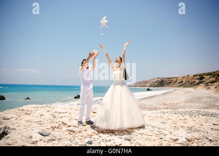 Happy smiling Bride and Groom libérant les mains blanches colombes sur une journée ensoleillée. Mer Méditerranée. Chypre Banque D'Images