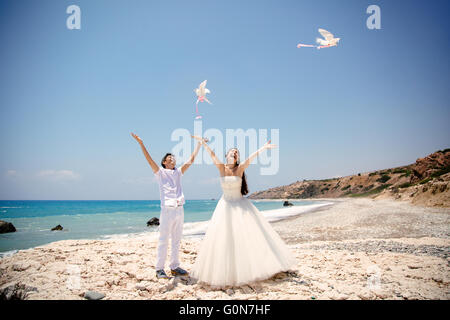 Happy smiling Bride and Groom libérant les mains blanches colombes sur une journée ensoleillée. Mer Méditerranée. Chypre Banque D'Images