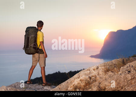 Homme avec sac à dos et à la recherche au lever du soleil Banque D'Images