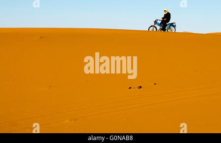 Un berber sur sa moto dans les dunes de sable de l'Erg Chebbi à Merzouga Banque D'Images