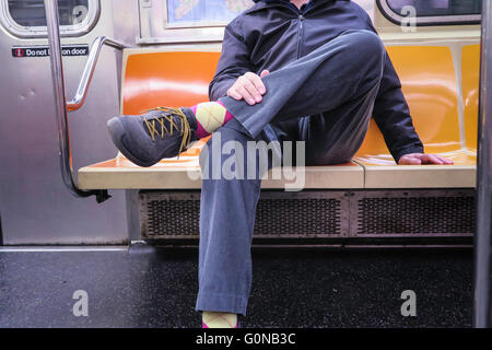 Homme d'arc plus d'un siège (homme) diffusion sur New York City métro (tube), NYC, USA Banque D'Images