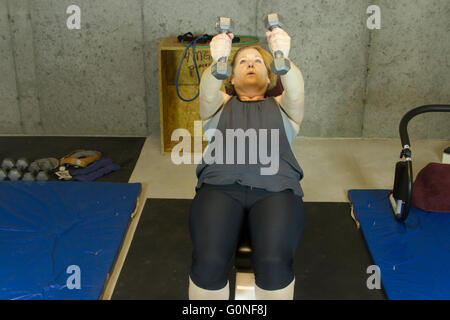 Femme mature en sous-sol salle de sport la levée de poids sur l'établi. Banque D'Images