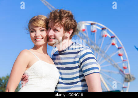 Vacances d'été et le bonheur concept. Les jeunes touristes couple aimant en plein air parc grande roue à l'arrière-plan Banque D'Images