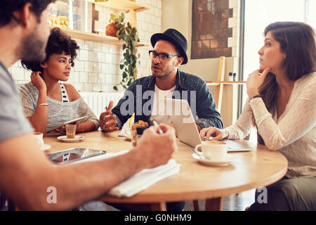 Portrait de jeunes amis assis dans un café et discuter. Rencontre des gens créatifs dans un café. Banque D'Images