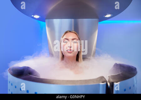 Portrait d'une belle jeune femme en cryosauna cabine pour la cryothérapie du corps entier. Les femmes de race blanche dans la pièce de refroidissement avec nit Banque D'Images