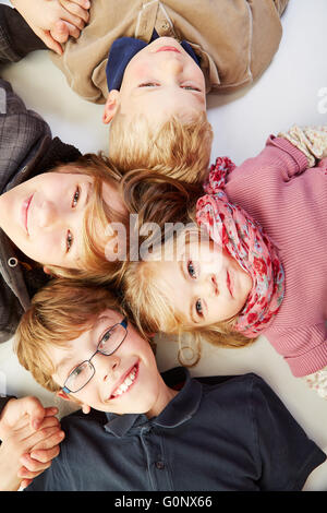 Quatre happy smiling children fixant dans un cercle et jusqu'à la Banque D'Images