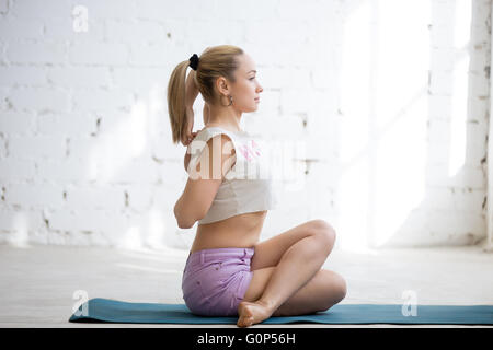 Vue de côté portrait of happy young woman doing yoga vêtements occasionnels à l'intérieur. Yogi girl working out Banque D'Images