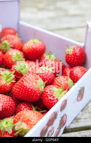 Fraises fraîches dans un carton à l'extérieur sur une table en bois Banque D'Images