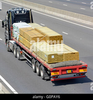 La logistique de transport par remorque articulée lit plat et de camions chargés de matériaux de construction en bois le long de la conduite d'autoroute English UK Banque D'Images