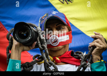 Caracas, Venezuela. 3 mai, 2016. Une femme avec la bouche couverte est titulaire d'un appareil photo et d'une chaîne au cours d'une marche pour la liberté de parole sur la Journée mondiale de la liberté de la presse à Caracas, capitale du Venezuela, le 3 mai 2016. © Boris Vergara/Xinhua/Alamy Live News Banque D'Images