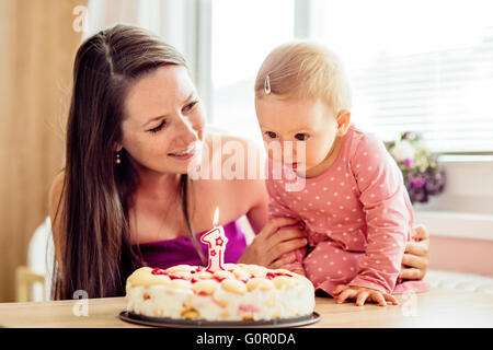 Mère tenant son bébé fille avec gâteau d'anniversaire Banque D'Images