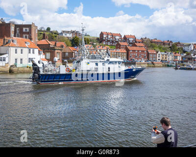 Gardien de l'Est du Nord **** La surveillance des pêches navire entrant dans le port de Whitby en passant un garçon de pêche avec une ligne à main. Banque D'Images