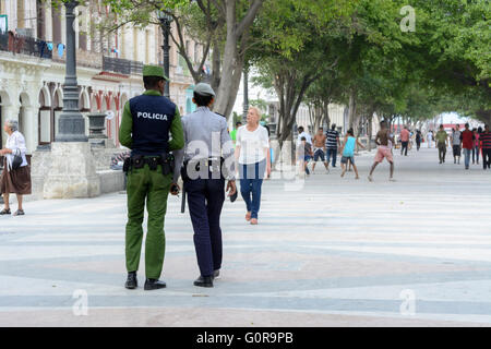 Deux agents de police patrouillant le Prado à La Havane, Cuba pendant que les enfants jouent au football Banque D'Images