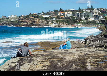 Les gens assis sur les rochers au bord de l'océan dans la région de Sydney, Tamarama. Banque D'Images