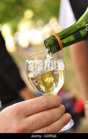 L'homme se verse dans un verre de vin blanc Banque D'Images