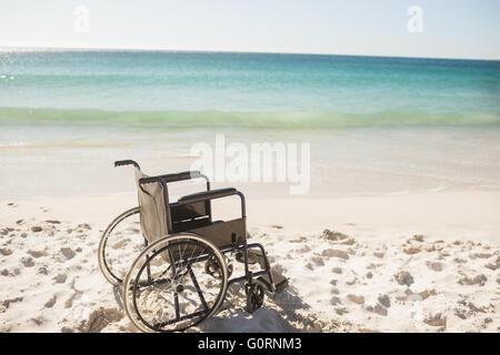 Fauteuil roulant noir sur la plage Banque D'Images