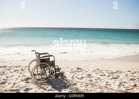 Fauteuil roulant noir sur la plage Banque D'Images