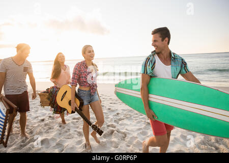 Les amis portant un panier et de surf Banque D'Images