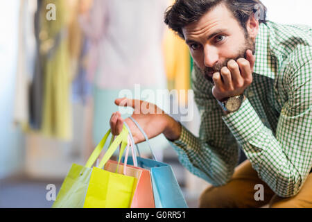 Bored man with shopping bags tout en femme par porte manteau Banque D'Images