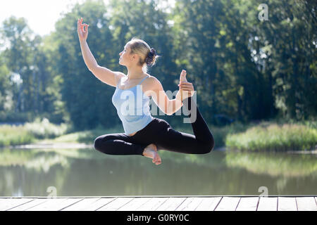 Serene young belle femme flottant dans les airs au cours de la pratique du yoga, de léviter au-dessus du terrain en Eka Pada Rajakapotasana Banque D'Images