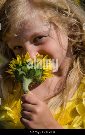 Portrait de l'adorable petite fille blonde qui sent le tournesol jaune Banque D'Images