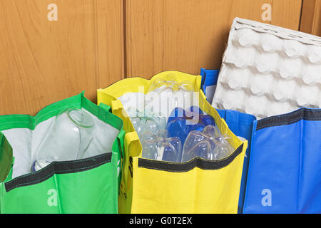 Vert, bleu et jaune des sacs pour le tri des déchets ménagers sont remplis de déchets - papier, plastique et verre. Banque D'Images