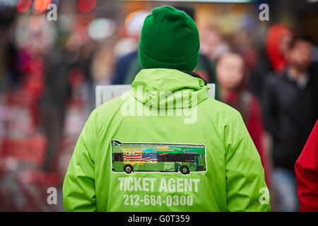 New York Times Square uniforme vert la vente de billets de bus hop on off représentant l'ombre des circuits en autocar, le vendeur signe avec stoppi Banque D'Images