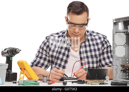 Technicien PC mâle la réparation d'un ordinateur de bureau et de mesurer la résistance électrique isolé sur fond blanc Banque D'Images