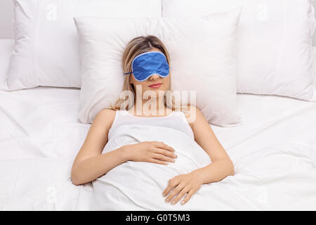 Jeune femme dormir sur un lit confortable avec blue eye mask Banque D'Images