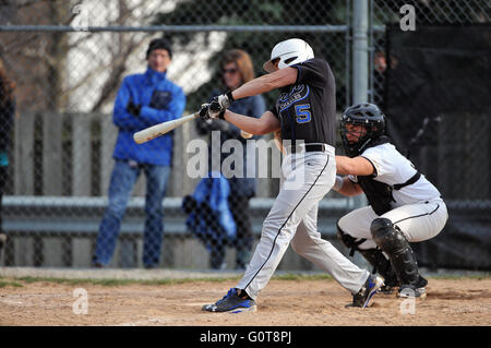 Un frappeur fait suite à son swing à la suite de la prise de contact avec un pas pendant un match de baseball de l'école secondaire. USA. Banque D'Images