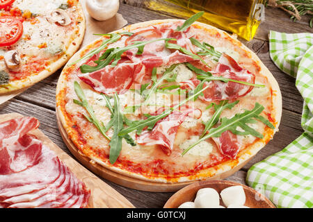 Pizza au prosciutto et à la mozzarella et aux tomates et champignons sur table en bois Banque D'Images