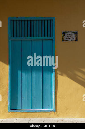 Porte turquoise et jaune mur avec petit panneau de porte par Banque D'Images