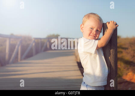Portrait of a smiling boy standing on boardwalk Banque D'Images