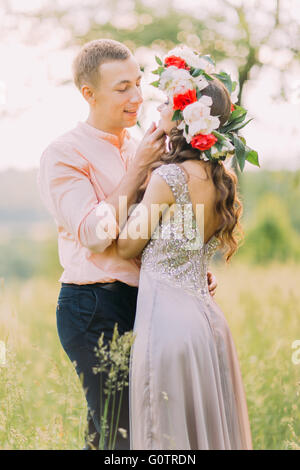 Bel homme légèrement en contact avec le visage de sa petite amie wearing wreath in garden Banque D'Images