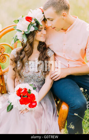 Photo en gros plan de la mode cool couple embracing on vintage en bois chaise dans le jardin Banque D'Images