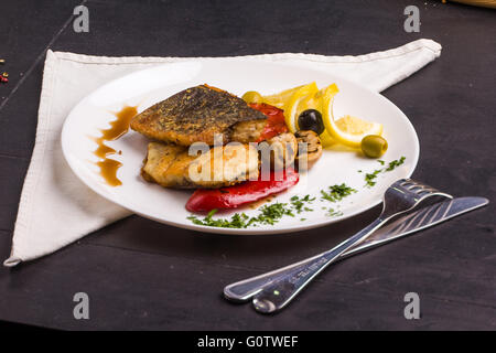 Concept : alimentation saine. Des poissons grillés steak et légumes sur un plat avec des ingrédients et des couverts autour Banque D'Images