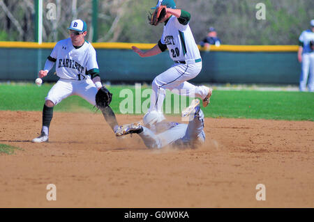 Un arrêt-court en attente d'un lancer à la fin de la deuxième base alors que le second sous-bondit au-dessus d'un coureur qui a plongé dans l'arrivée en toute sécurité. USA. Banque D'Images