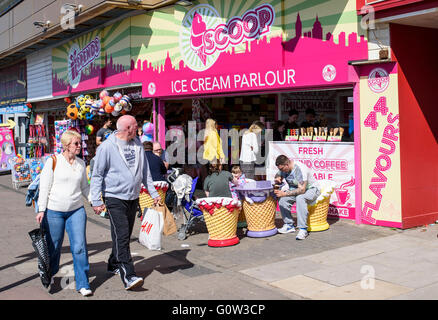 Un couple marche passé aux personnes bénéficiant d'une glace à l'écope glacier sur la promenade de Blackpool, lancashire, uk Banque D'Images