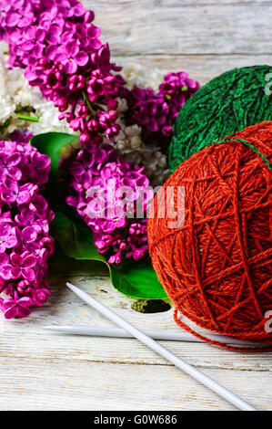 Boules de fil de laine à tricoter et branches de fleurs lilas Banque D'Images