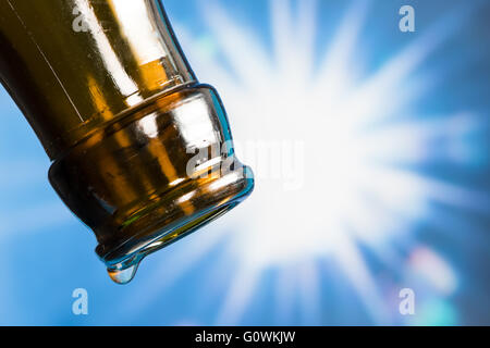 Dernière goutte d'une bouteille de bière vide avec le soleil en arrière-plan Banque D'Images