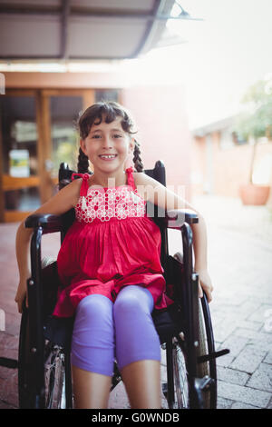 Jeune fille souriante de l'emplacement dans un fauteuil roulant Banque D'Images