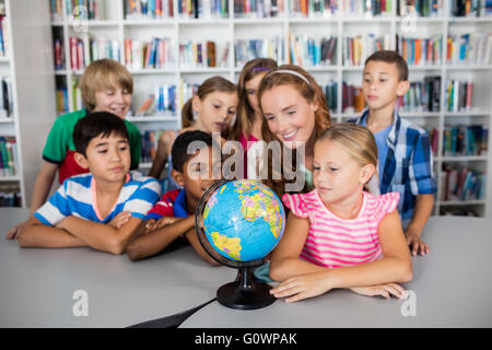 Enseignant et élèves looking at a globe Banque D'Images